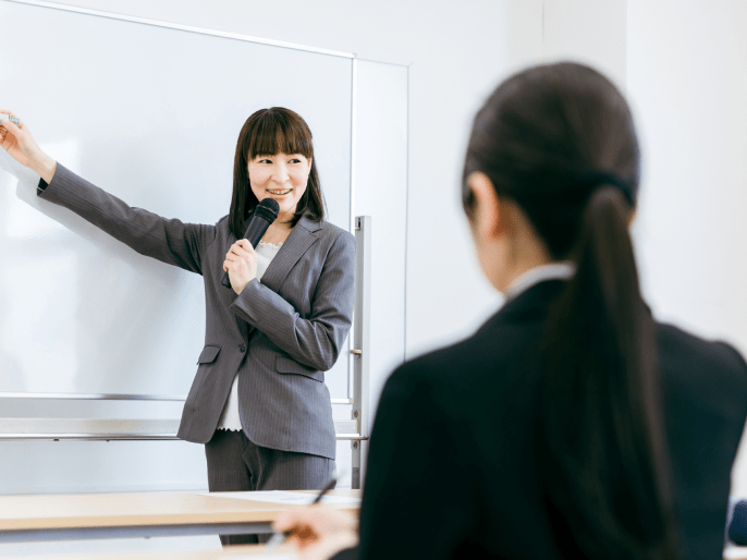 ホワイトボードの前で女性が話している写真